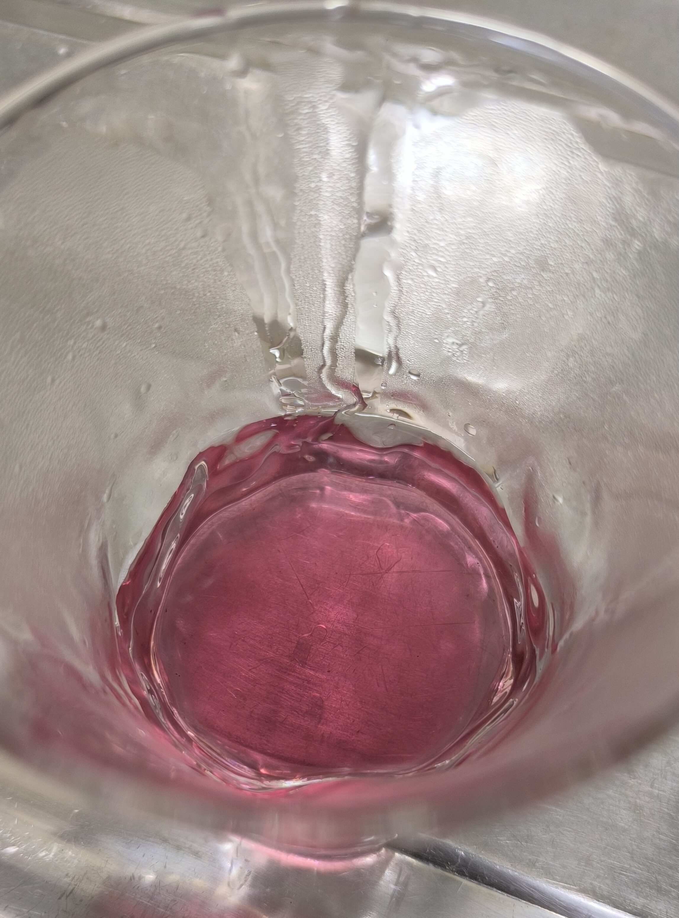 透き通ったピンク色の赤しそ抽出液を30ml計量している様子