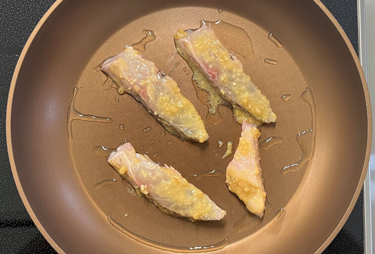 フライパンで白身魚を焼いている様子