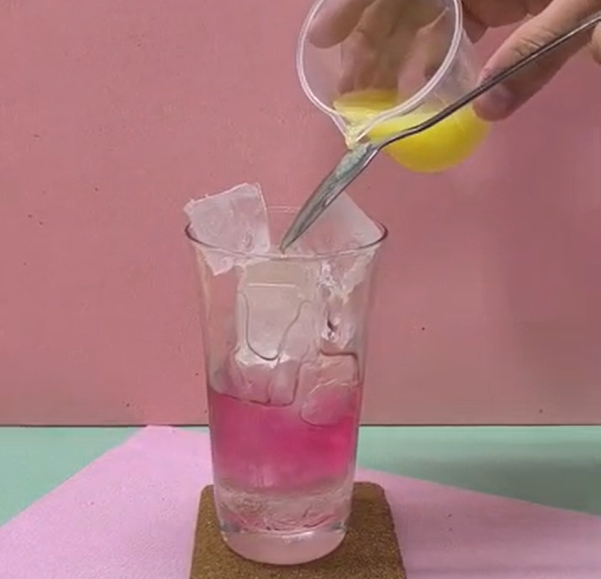 スプーンの背を使って上層の青切りシークヮーサーと炭酸を静かに注いでいる様子